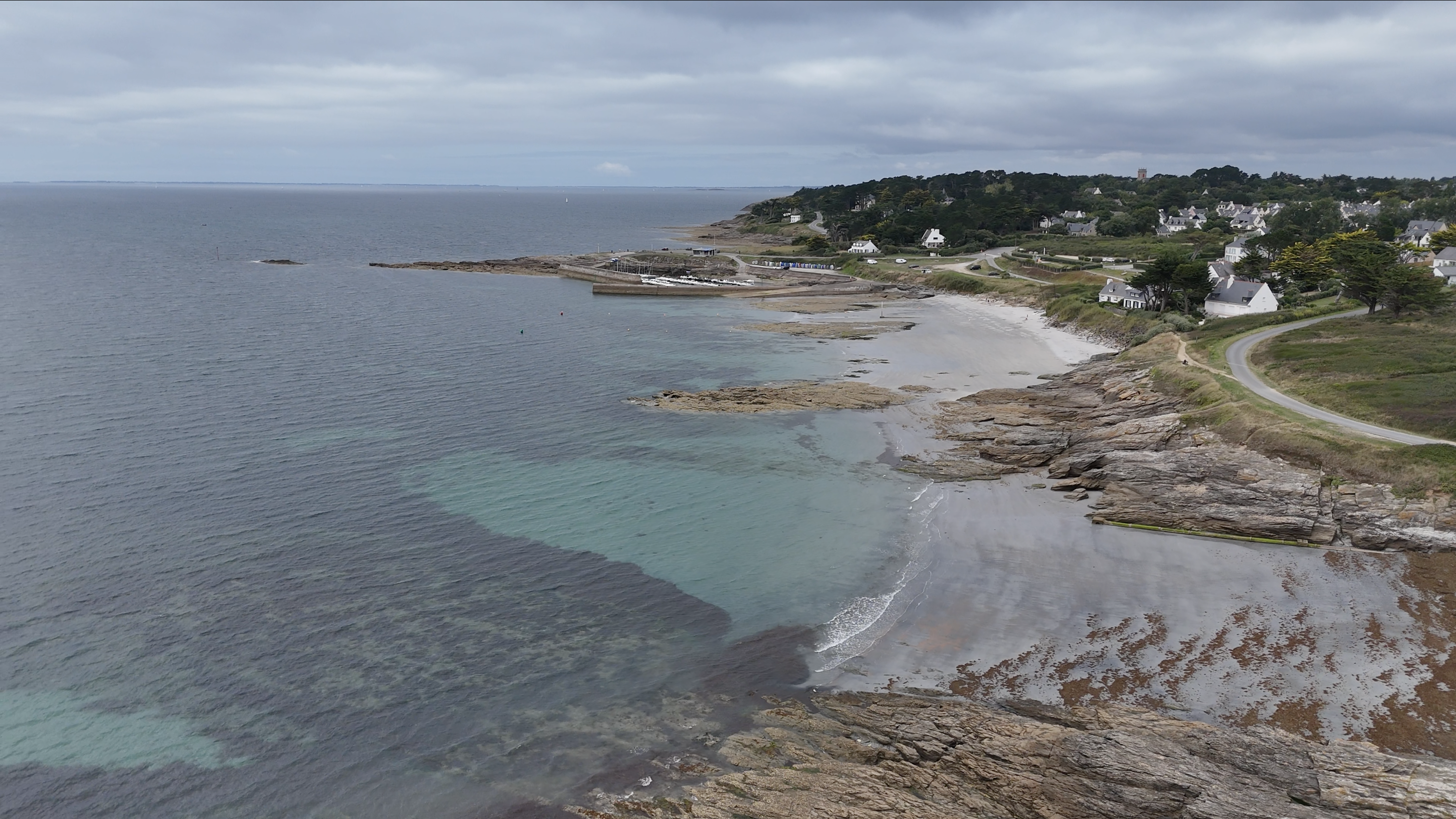 photo aérienne basse altitude, côte du Morbihan : maisons blanches, plage, rochers s'avançant sur la mer